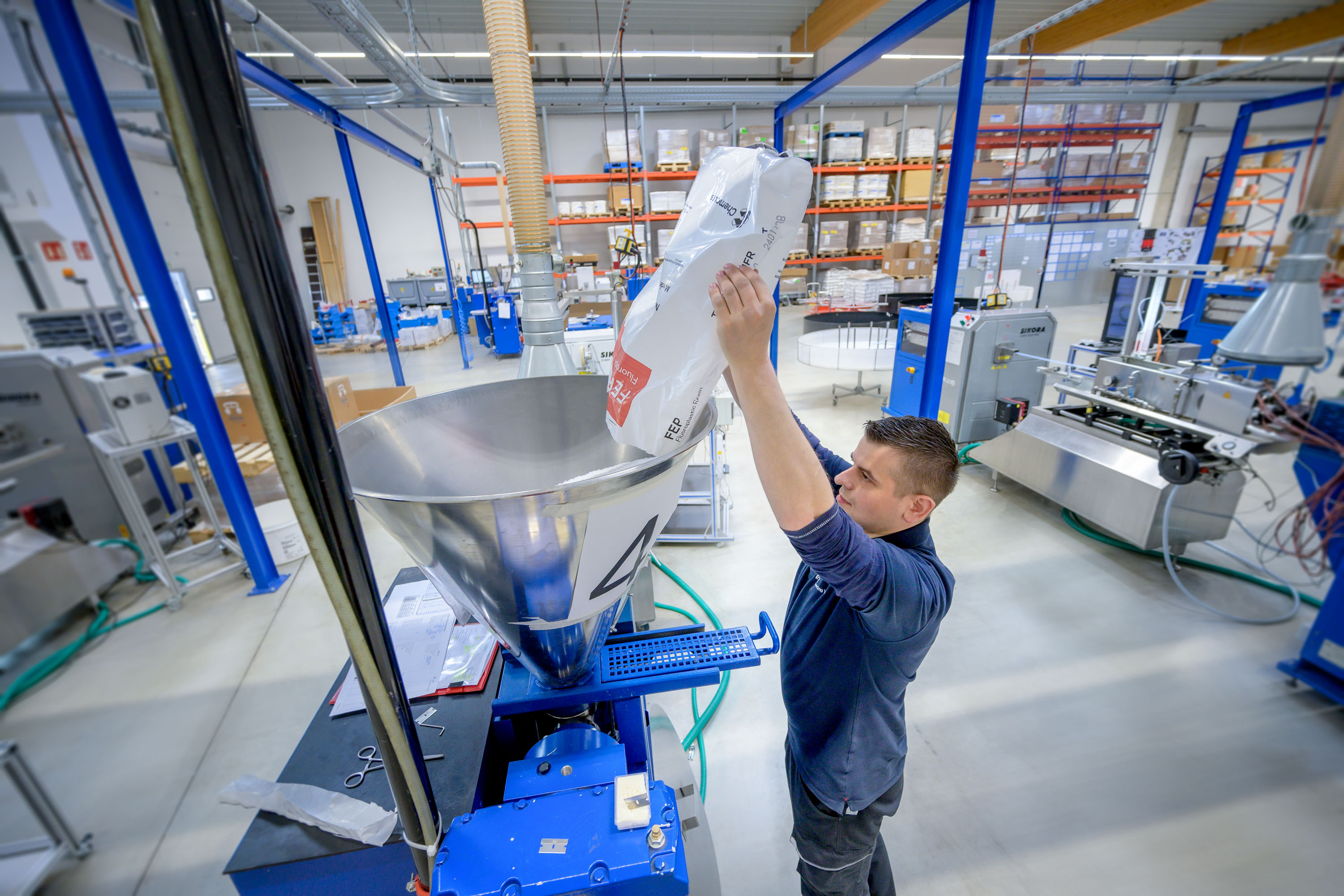 Foto aus der APT Produktion: Mitarbeiter füllt Material in den Extruder